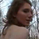 A red-headed woman takes a piss and shit in the woods with her ass towards the camera.